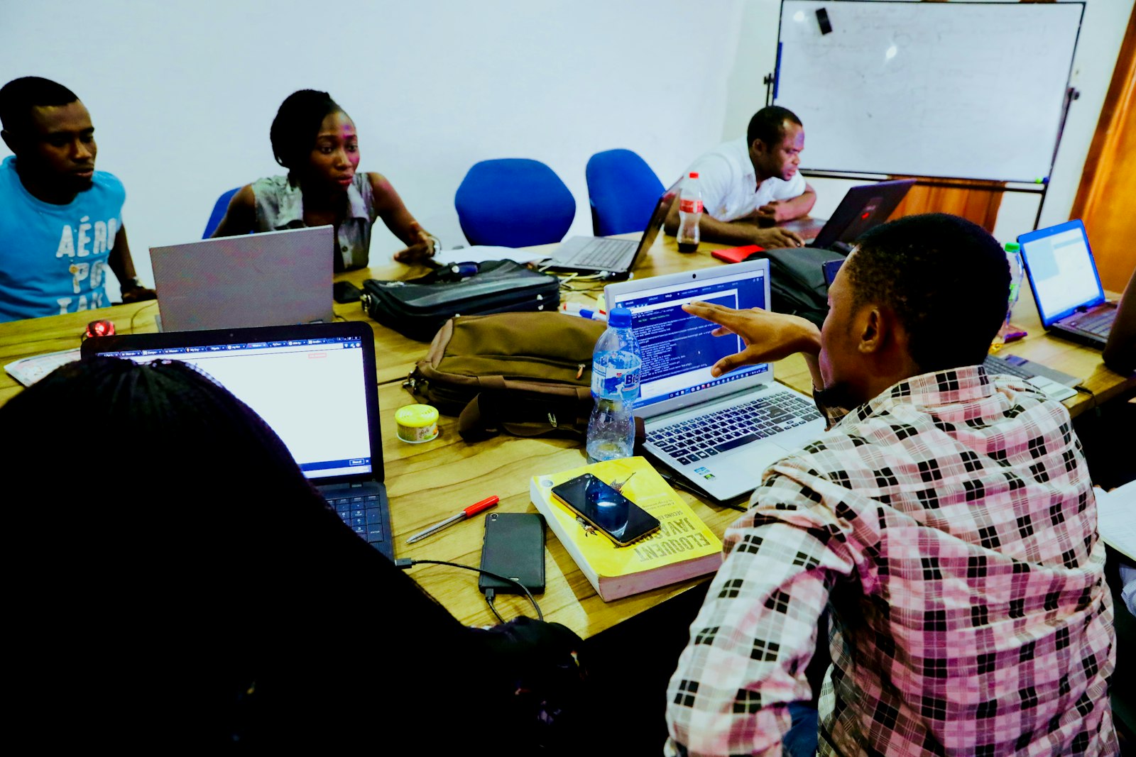 A team around a table of laptops talk through code in Lagos
