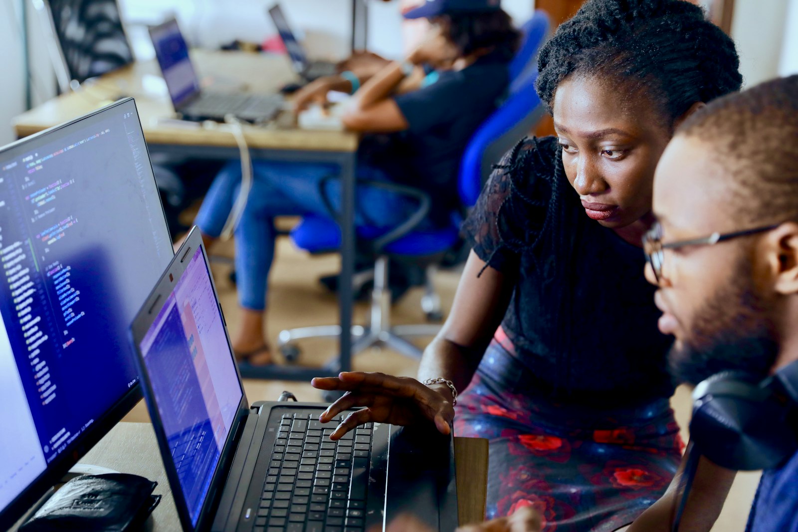 Two people work through code together at a laptop in a Lagos coworking space