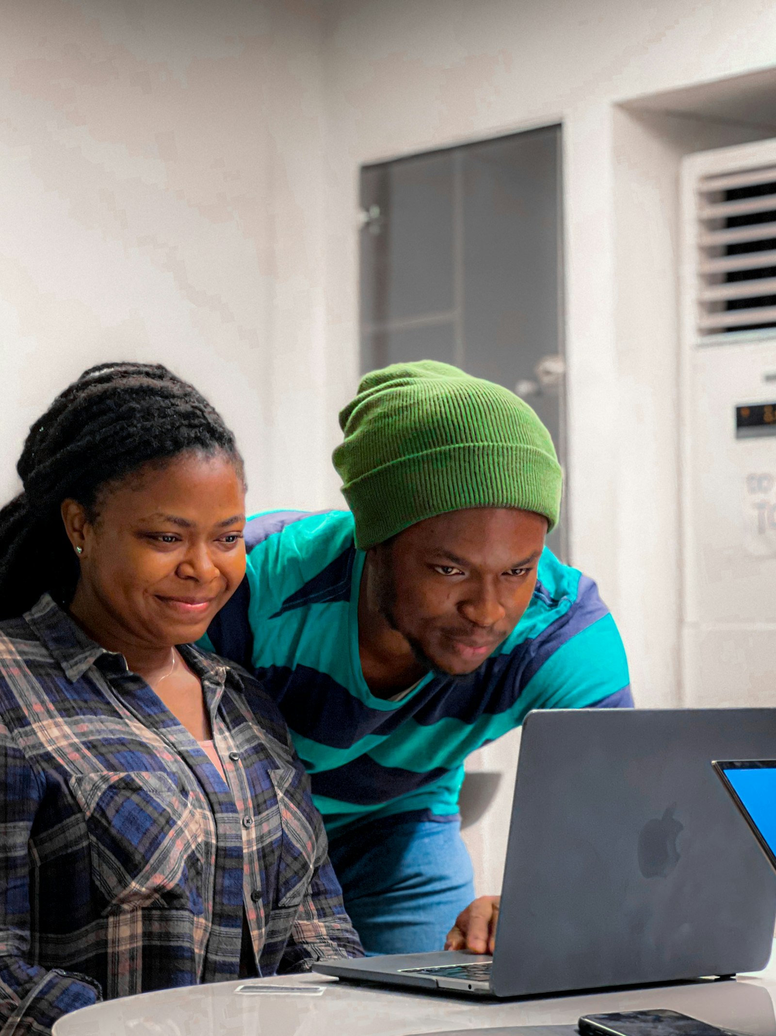 Two people smile at a laptop screen in an office in Lagos